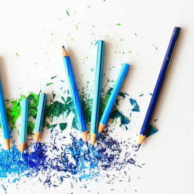 Creative display of colored pencils and vibrant shavings on a white background.